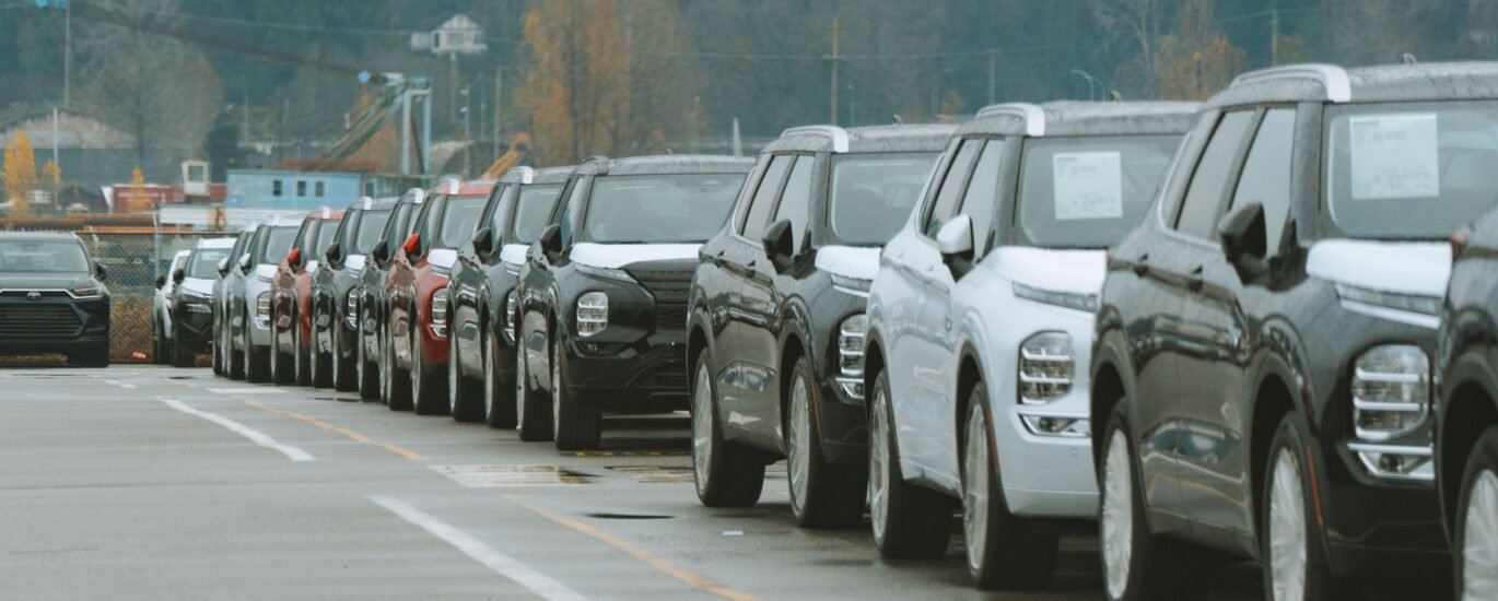 Row of new cars in a dealership lot representing buying a car with crypto